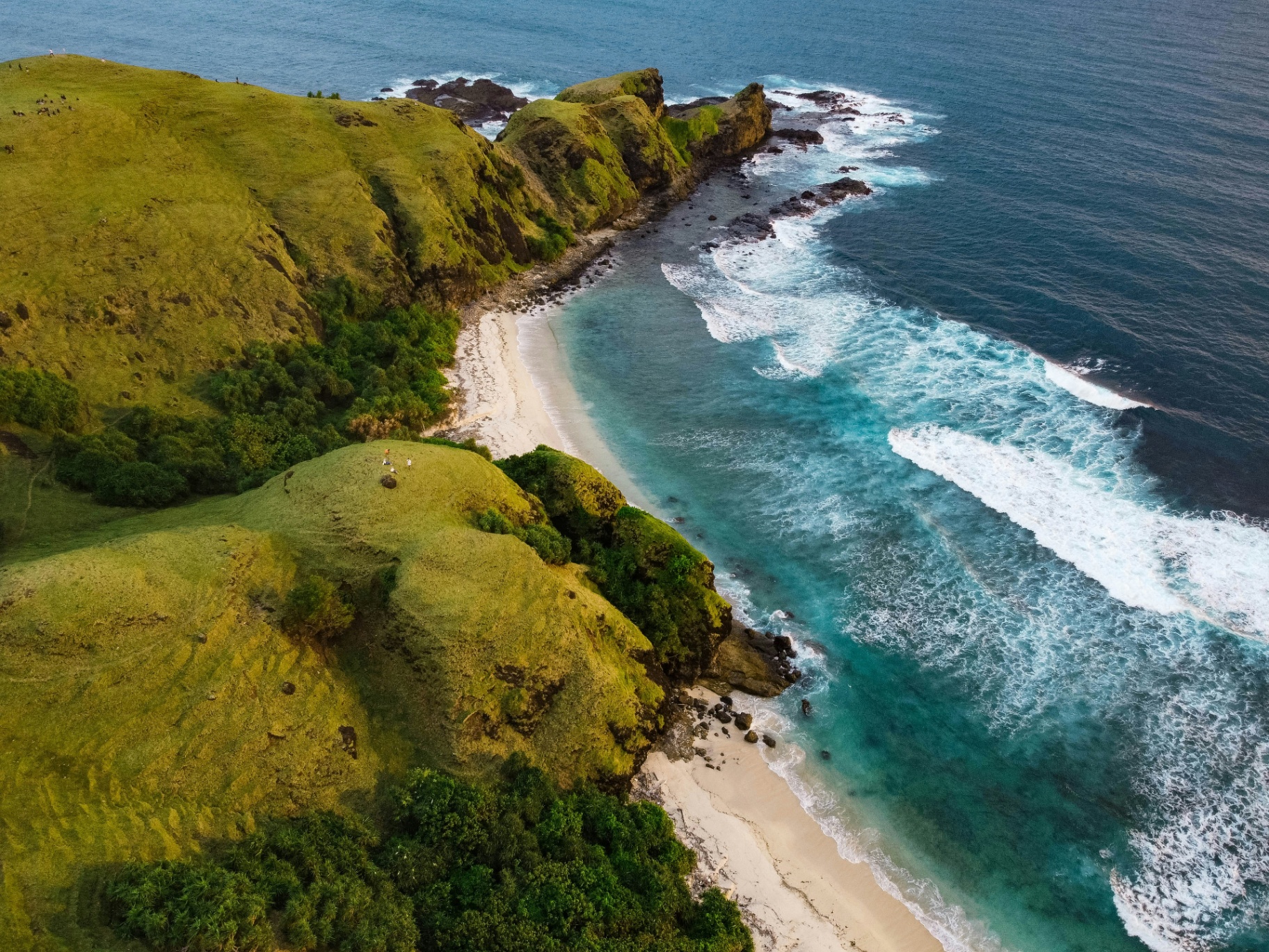 Aerial view of green cliffs and surf breaks along the Kuta Lombok coast