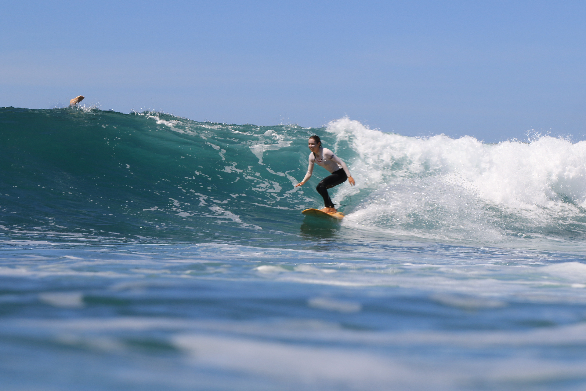 Student surfing a clean wave on a yellow softboard